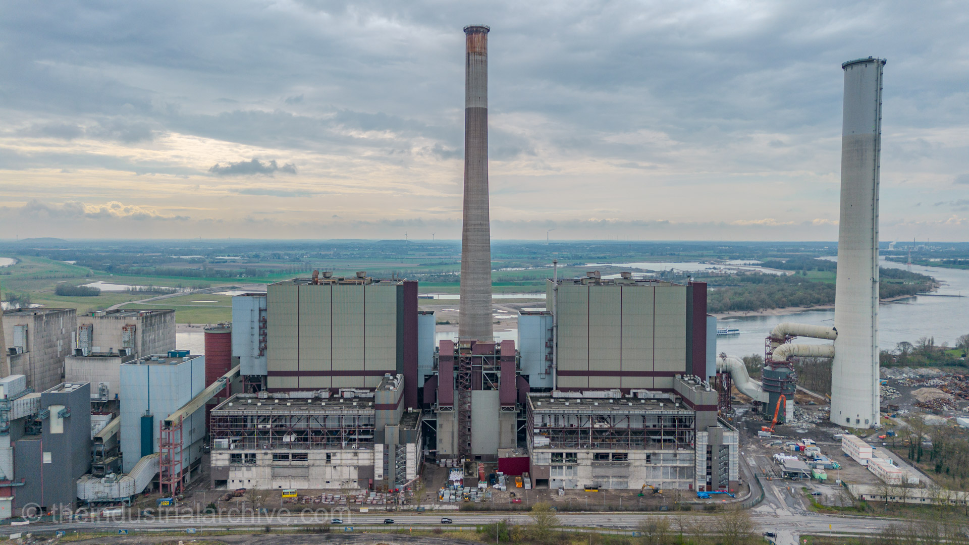 Aerial overview of Voerde Power Station during demolition, with stripped turbine halls, central smokestack, and Rhine River in background, captured for The Industrial Archive blog.